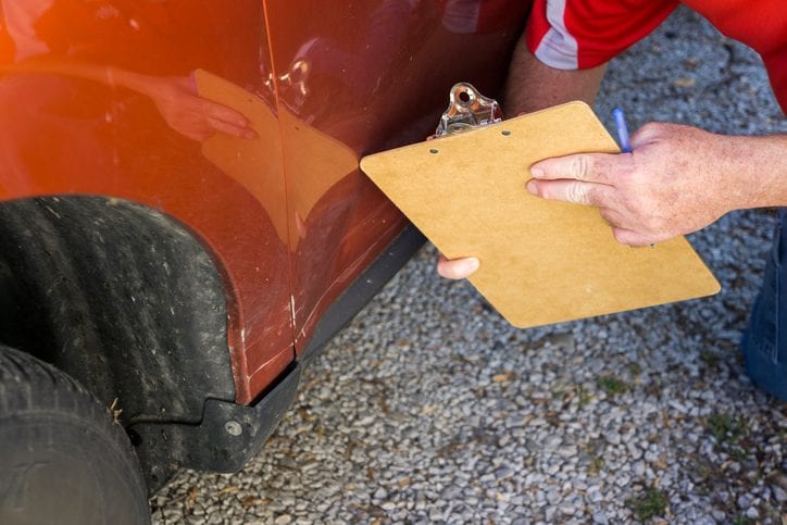 Carolina Collision and Frame Service | Mechanic holding a clipboard while going over damage to a rust colored car
