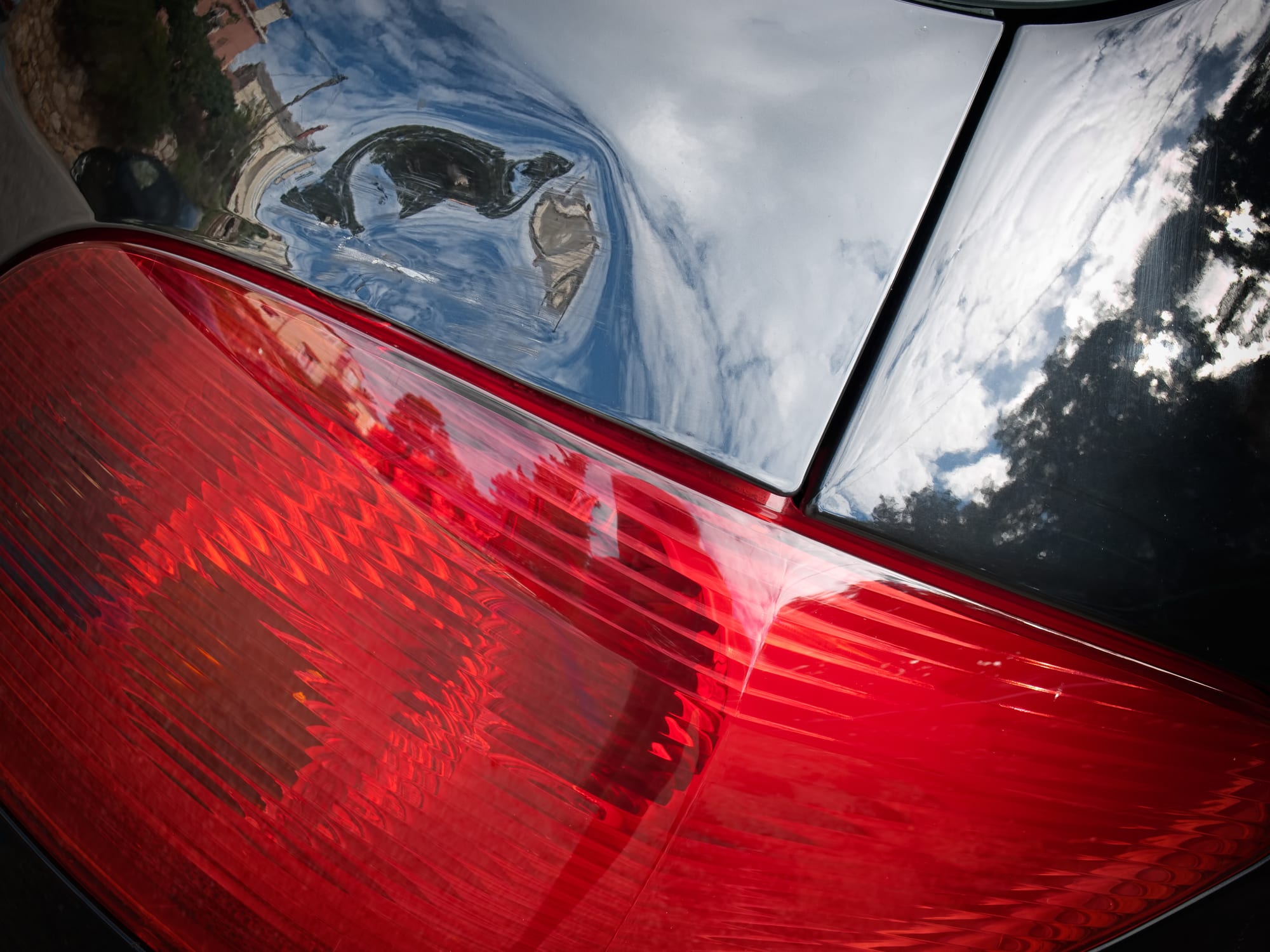 Carolina Collision and Frame Service | Red tail light on a black car with a dented panel