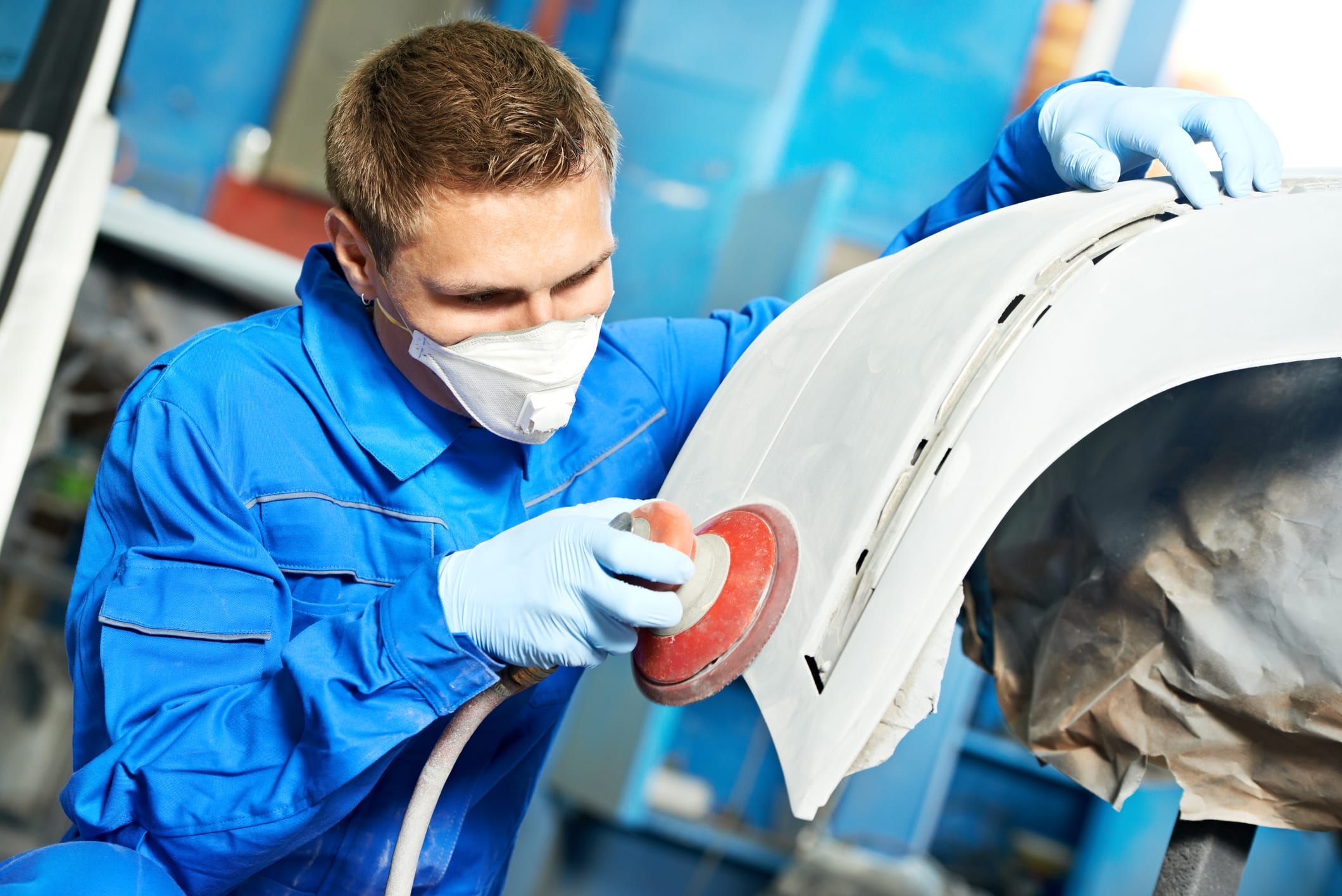 Carolina Collision and Frame Service | Auto body repair technician buffing the panel of a car and wearing a mask and gloves