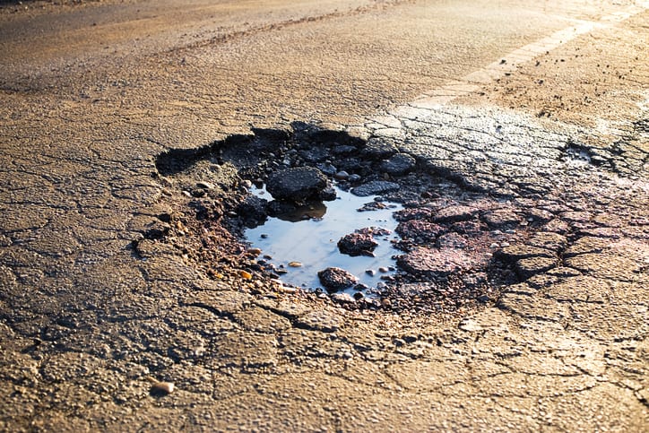 Carolina Collision and Frame Service | Pot hole filled with water in a road
