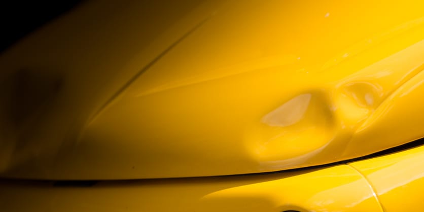 Carolina Collision and Frame Service | Close up of a dented yellow fender on a vehicle