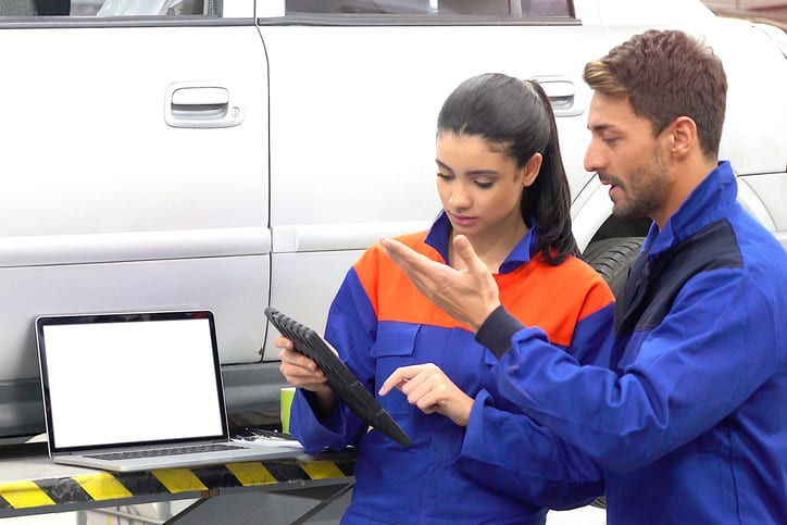 Carolina Collision and Frame Service | Two service techs going over details of repair work and specs of a white car on a laptop in an auto body shop