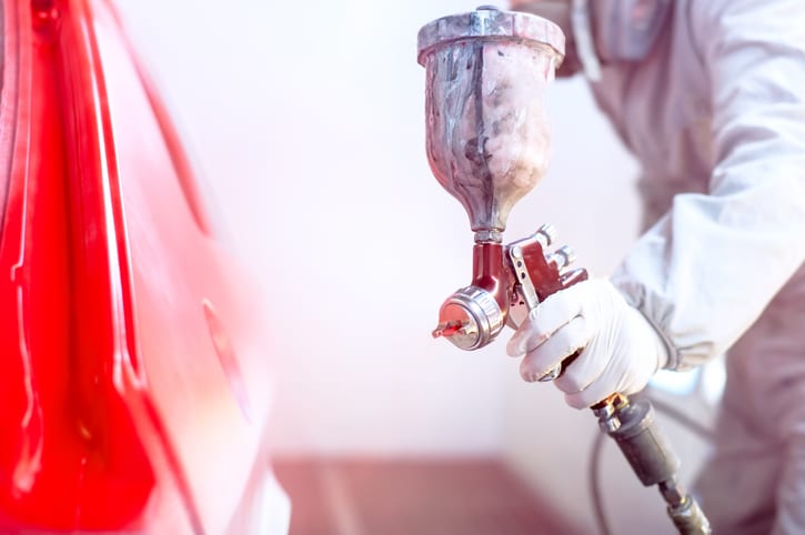 Carolina Collision and Frame Service | Close up of a spray gun spraying red paint on the side of a car
