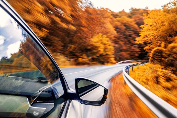 Carolina Collision and Frame Service | Car driving on a windy highway with fall scenery of gold leaves on trees