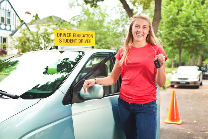 Carolina Collision and Frame Service | Girl wearing a red shirt standing beside a driver education student car holding keys and smiling