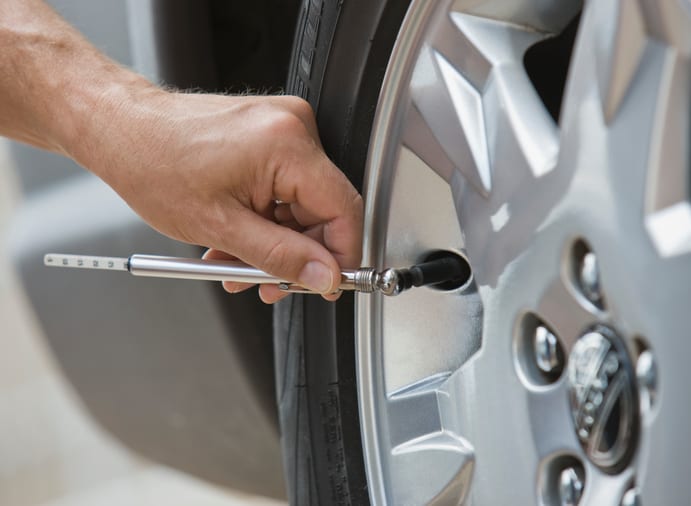 Carolina Collision and Frame Service | Close up of a man's hand checking the air pressure of a tire