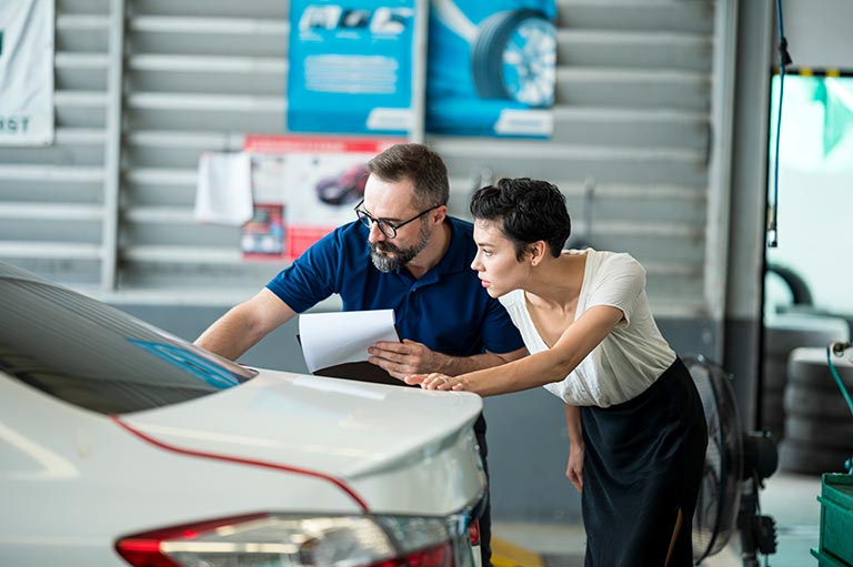 Carolina Collision tech answering questions. Carolina Collision tech explaining damage of car exterior to customer at Auto Repair Center. Business hour 24/7 service coverage. Customer Service, Quality of Service.