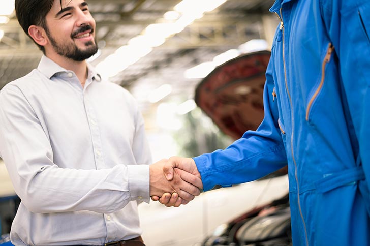 Carolina Collision technician shaking hands with vehicle owner customer after sending car for repairing or check at Carolina Collision And Frame Service.