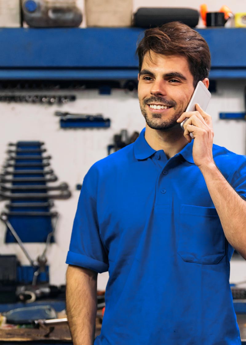 Carolina Collision and Frame Service | Mechanic talking on a cell phone wearing a blue shirt