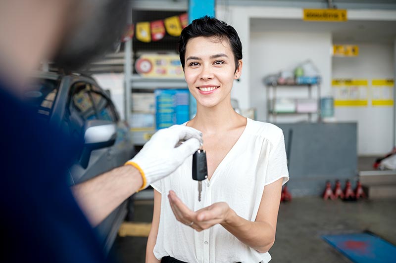 Carolina Collision and Frame Service | Mechanic giving a happy customer wearing a white shirt her car keys in an auto shop