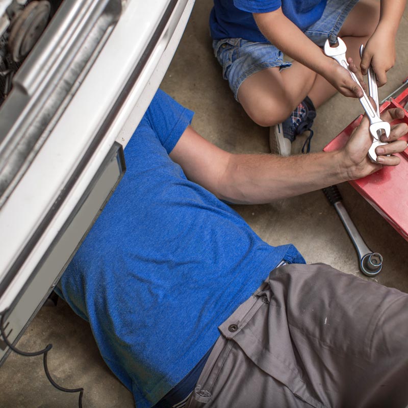 Carolina Collision and Frame Service | Torso of a mechanic underneath a car doing auto repair work