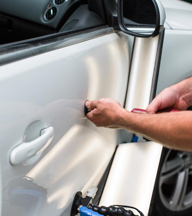 Carolina Collision and Frame Service | Mechanic repairing a small dent in the side of white car